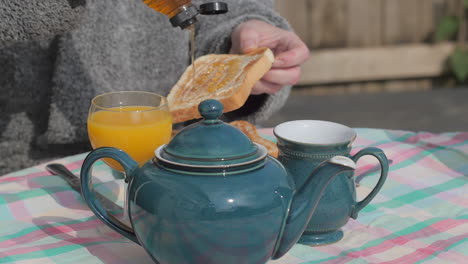 Person-pours-honey-on-buttered-toast-at-English-breakfast,-slow-motion