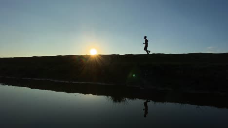 Young-man-jogging-at-morning-during-sunrise-beside-a-lake