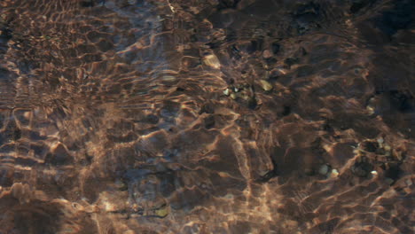 Close-up-time-lapse-of-a-clear-water-stream-,-showing-ripples-and-reactions,-while-gradually-getting-darker
