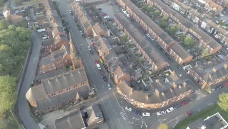 Drone-aerial-birds-eye-perspective-above-British-town-houses---church-with-steeple-at-sunrise-orbit-left