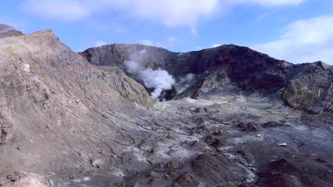 White-Island-volcanic-crater-with-distant-smoke-rising,-aerial