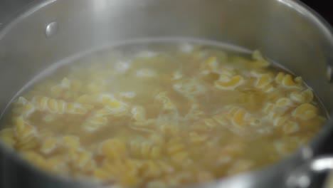 Pasta-in-boiling-water-inside-a-silver-pot-as-steam-rises