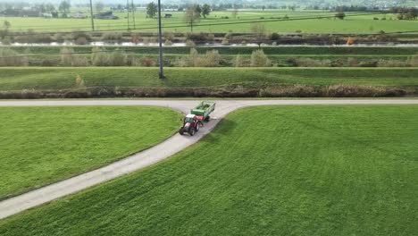 Aerial-View-Of-Farm-Tractor-Pulling-Trailer-Turning-Into-Road-In-Rural-Benken,-Switzerland