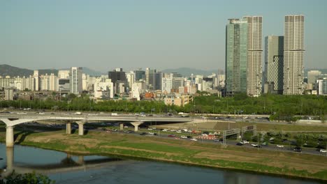 Car-traffic-at-Eungbonggyo-Bridge-and-Seoul-freeway-and-Hanwha-Galleria-Pore,-Acro-Seoul-Forest-skyscrapers-from-High-point-of-view