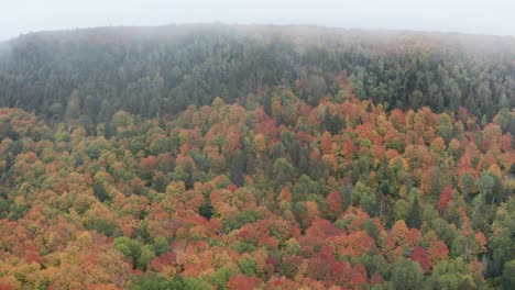 Drone-flying-through-clouds-towards-Oberg-Mountain-in-Minnesota,-over-a-spectacular-autumnal-forest-vista