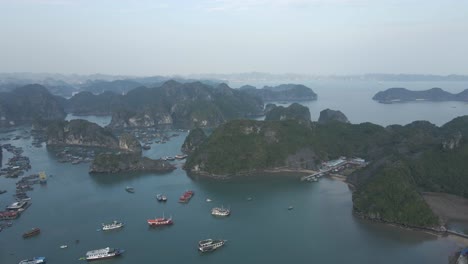 Aerial-pan-over-moored-tour-boats-and-floating-village,-Vietnam
