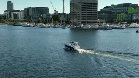 Drone-shot-of-a-boat-traveling-through-South-Lake-Union-in-Downtown-Seattle