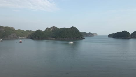 Low-aerial-beach-flight-to-large-tour-boat-moored-in-Ha-Long-Bay