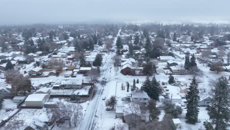Wide-aerial-view-of-the-main-street-passing-through-town-covered-in-snow