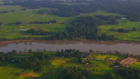 Vista-Aérea-Del-Río-Surma-Que-Atraviesa-Campos-Verdes-Rurales-En-Sylhet,-Bangladesh