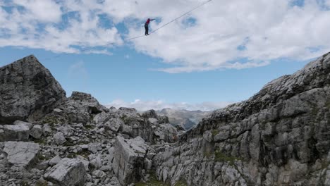 Aerial-flight-below-person-balancing-on-slackline-in-Dolomites-Mountains---Spectacular-mountain-range-view-with-green-valley-in-Italy