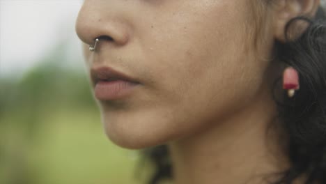 A-rack-focus-close-up-shot-of-the-face-of-a-young-attractive-Asian-female-outdoors-in-a-field,-India