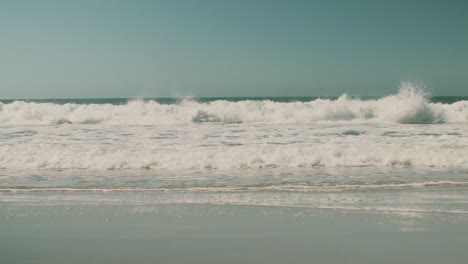 Huge-waves-break-on-the-shore-of-a-beach-in-Nazarè,-Portugal