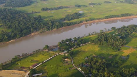 Aerial-View-Of-Surma-River-Running-Through-Rural-Green-Countryside-Fields-In-Sylhet,-Bangladesh