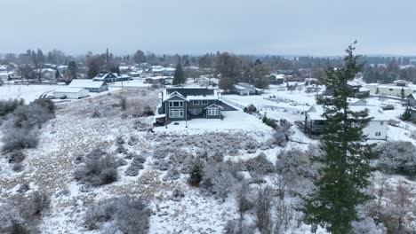 Wide-aerial-view-of-a-large-house-perched-on-a-ledge-with-snow-everywhere
