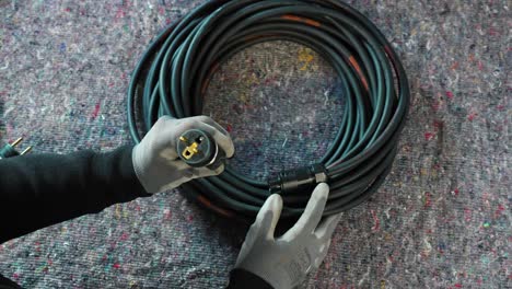 Electrician-with-gloves-on-checking-if-the-newly-made-rolled-up-electric-plug-is-perfect-to-sell