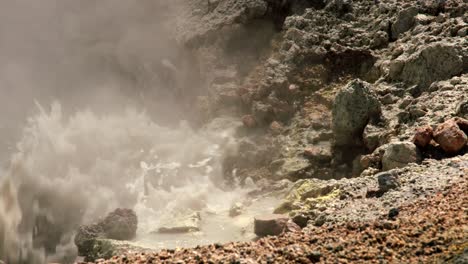 Boiling-geothermal-liquid-bubbling-onto-rocks,-close-up