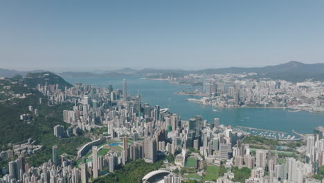 Aerial-wide-crane-shot-over-Victoria-Harbour,-with-Hong-Kong-Island-on-the-left-and-Kowloon-on-the-right
