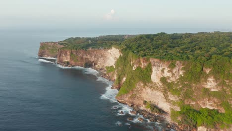 Aerial-drone-view-of-sea-side-cliffs-covered-with-green-forest