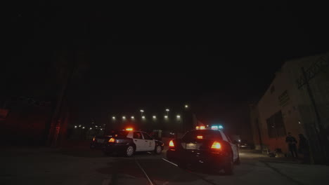 Turning-FPV-shot-of-2-police-cars-with-flashing-lights-pulling-over-a-car-at-night-time