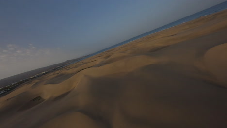 Flying-FPV-drone-over-sand-dunes-at-sunset,-Maspalomas