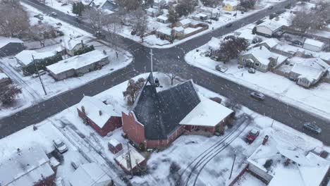 Aerial-view-of-snow-actively-falling-on-a-church-in-Spokane,-Washington