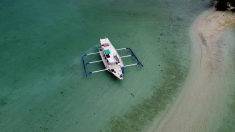 Orbit-shot-of-a-lone-boat-anchored-along-white-sandbar