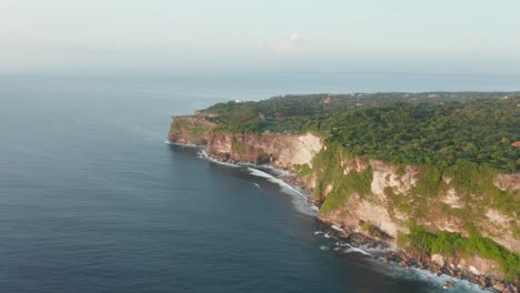 Aerial-drone-view-of-tall-sea-side-cliffs-covered-with-green-forest