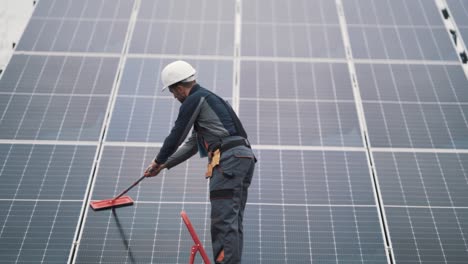 Rear-view-of-male-worker-washing-solar-panels
