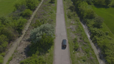 Drone-shot-view-of-black-car-driving-on-rural-road