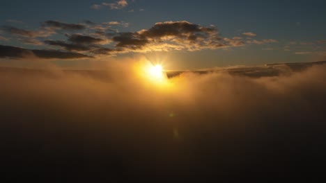 Schwenken-Der-Luftaufnahme-Der-Sonne-über-Den-Wolken-In-Zeitlupe,-Während-Einige-Wolkenfetzen-Vor-Der-Sonne-Vorbeiziehen