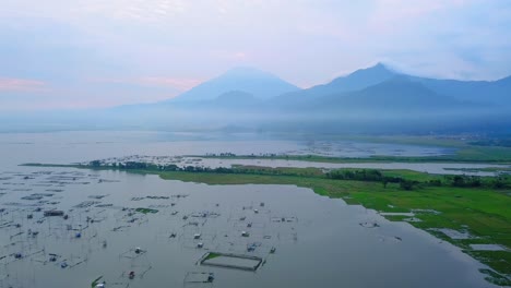Vista-Aérea-Del-Hermoso-Paisaje-Tropical-Con-Vistas-A-Muchas-Jaulas-De-Peces-En-El-Enorme-Lago-Y-Montaña-En-El-Fondo---Lago-Rawa-Pening,-Indonesia