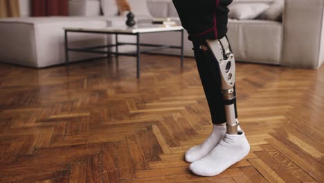 Disabled-person-with-a-prosthetic-leg-doing-rehabilitation-exercises-at-home,-bionic-leg-close-up