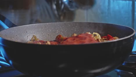 Pouring-tomato-sauce-into-a-wok-with-meat-and-vegetables-for-mexican-tortillas-and-mixing-it-all-with-a-wooden-spoon