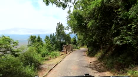 Safari-vehicle-driving-in-paved-road-down-to-Ngorongoro-Caldera,-shot-from-car