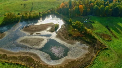 Aerial-view-of-a-pond-in-a-farmland-field-in-autumn---low-water-level-due-to-drought