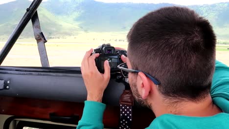 Young-traveler-checking-camera-photos-during-a-4x4-safari-trip-in-Tanzania,-Africa