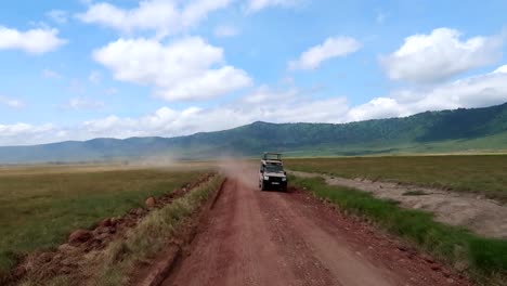 Two-vehicles-passing-in-Ngorongoro-Crater-with-dusty-roads-and-mountainous-landscape