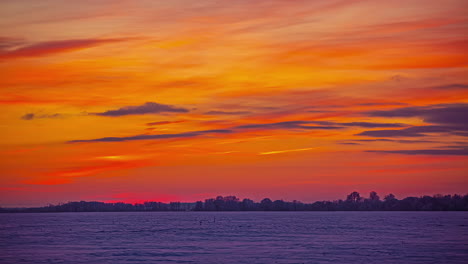 Zeitrafferaufnahme-Des-Orangefarbenen-Himmels-Bei-Sonnenuntergang-Mit-Fliegenden-Wolken-über-Der-Weißen-Winterlandschaft