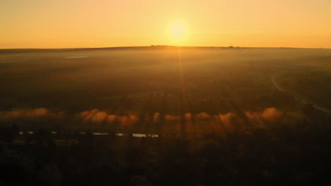 Landscape-aerial-drone-shot-of-an-amazing-yellow-sunrise-over-morning-fog-and-clouds,-in-Moldova-countryside