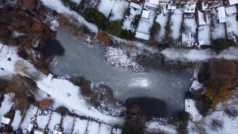 Top-down-aerial-birds-eye-view-frozen-lake-or-pond-in-park-in-England