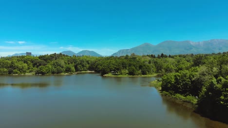 Bosques-De-árboles-Verdes-Y-Prados-En-El-Parque-Rodeados-De-Aguas-Tranquilas-Del-Lago-Sobre-Un-Fondo-De-Cielo-Azul-Brillante
