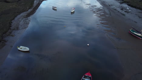 Long-Aerial-Drone-Shot-Flying-Over-Creek-at-Low-Tide-with-Sailing-Boats-in-North-Norfolk-on-Cloudy-Gloomy-Moody-Day-UK