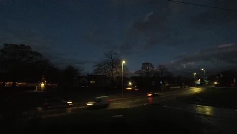 Gloomy-evening-storm-clouds-and-vehicle-headlights-passing-across-British-road-junction-time-lapse