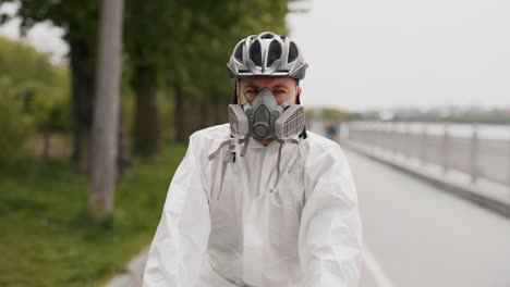 close-up-of-a-young-man-in-a-protective-suit,-mask-and-helmet-rides-a-bicycle