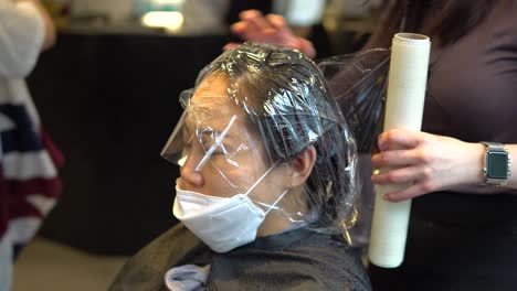 Hairdresser-put-on-plastic-wrap-on-Asian-woman-hair-at-the-beauty-salon-during-a-covid-19-pandemic