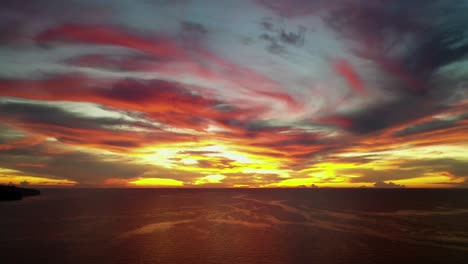 Dramatic-breathtaking-red-sunset-above-the-ocean,-panoramic-backwards-aerial