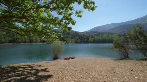 Rising-from-the-ground-towards-a-tree-we-see-two-kayaks-sit-on-the-shore-of-the-Tsivlos-Lake