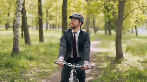 Happy-man-in-a-business-suit-on-a-bicycle-rides-in-the-park