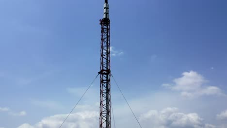 Top-down-aerial-view-of-a-microwave-relay-or-radio-and-cellular-tower-against-a-sky-and-cloud-background